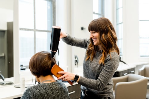 Imagem mulher sorrindo, penteando o cabelo de outra mulher